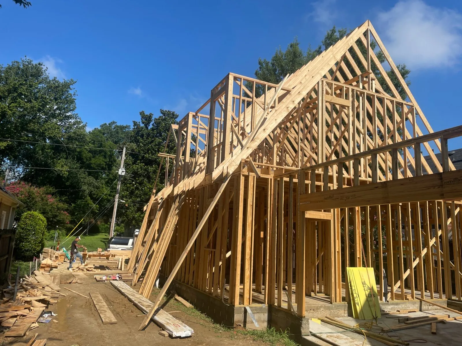 Crew raising the roof trusses on a wood-frame duplex under construction in Memphis, with lumber stacks and a completed neighbouring home behind