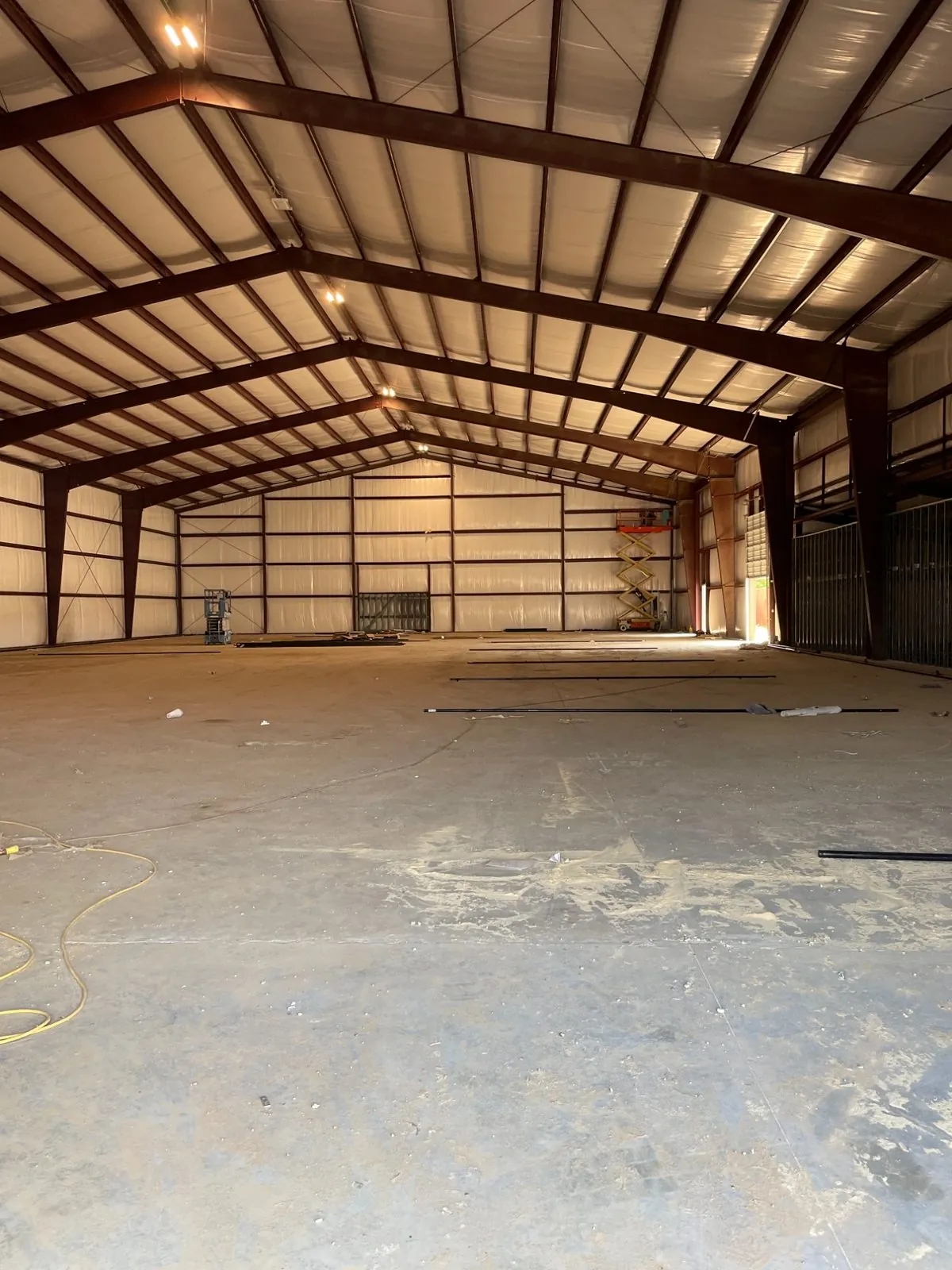 Enclosed metal building shell with exposed painted steel frame and insulated roof deck during construction